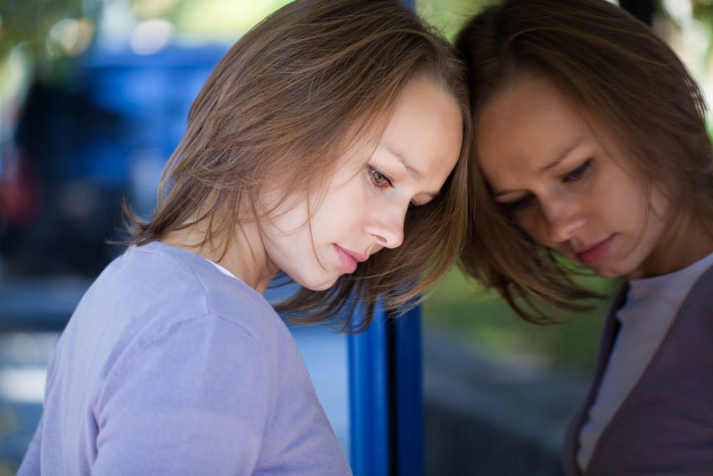 Sad woman leans against mirror